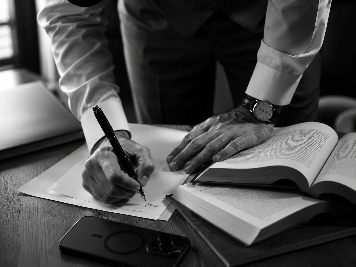 Abogado firmando un escrito judicial junto a un código abierto sobre el escritorio
